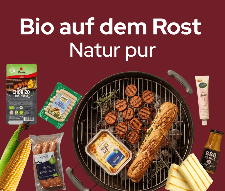 Grill mit veganen und Bio-Grillprodukten, darunter Würste, Mais und Soße vor dunkelrotem Hintergrund